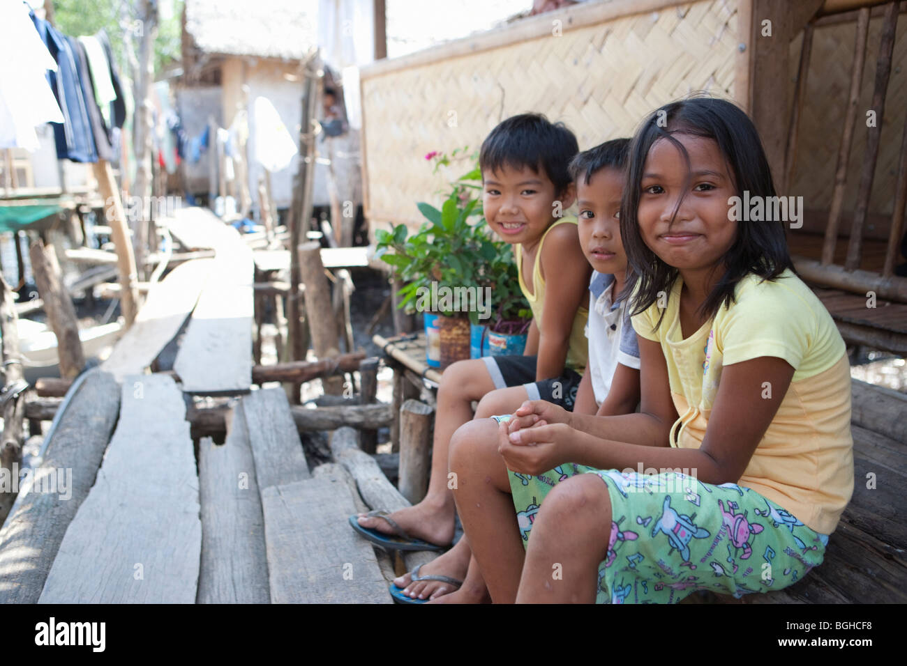 Trois enfants assis dans le passage libre entre les maisons de pêcheurs ; ville ; l'Île Coron Busuanga, Philippines Banque D'Images