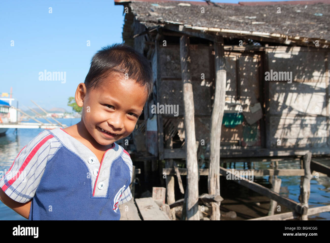 Filipino boy smiling in front of guindé ; maison de ville ; l'Île Coron Busuanga, Philippines. Banque D'Images