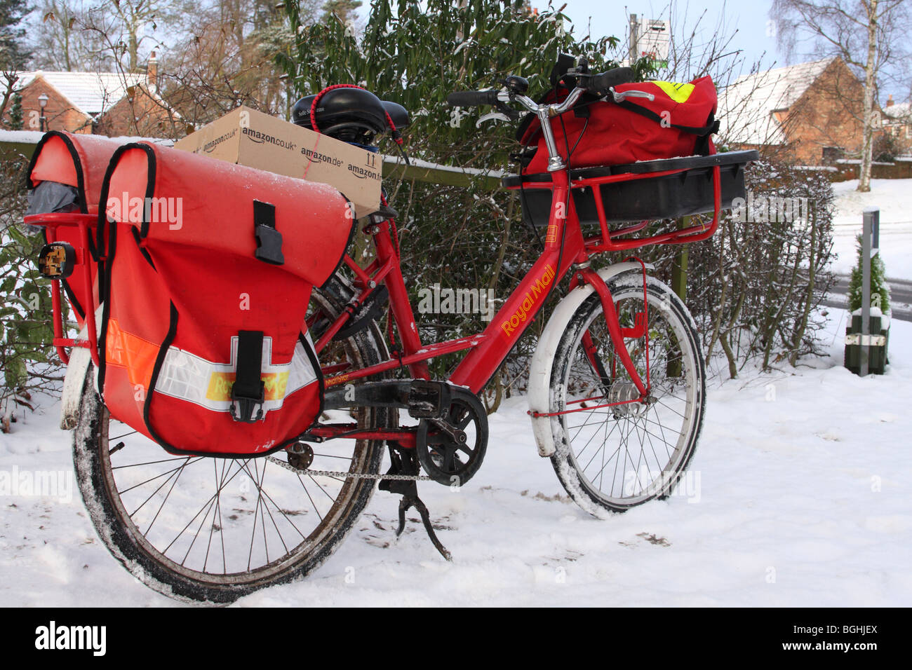Royal Mail a bicyclette dans un village anglais en hiver. Banque D'Images