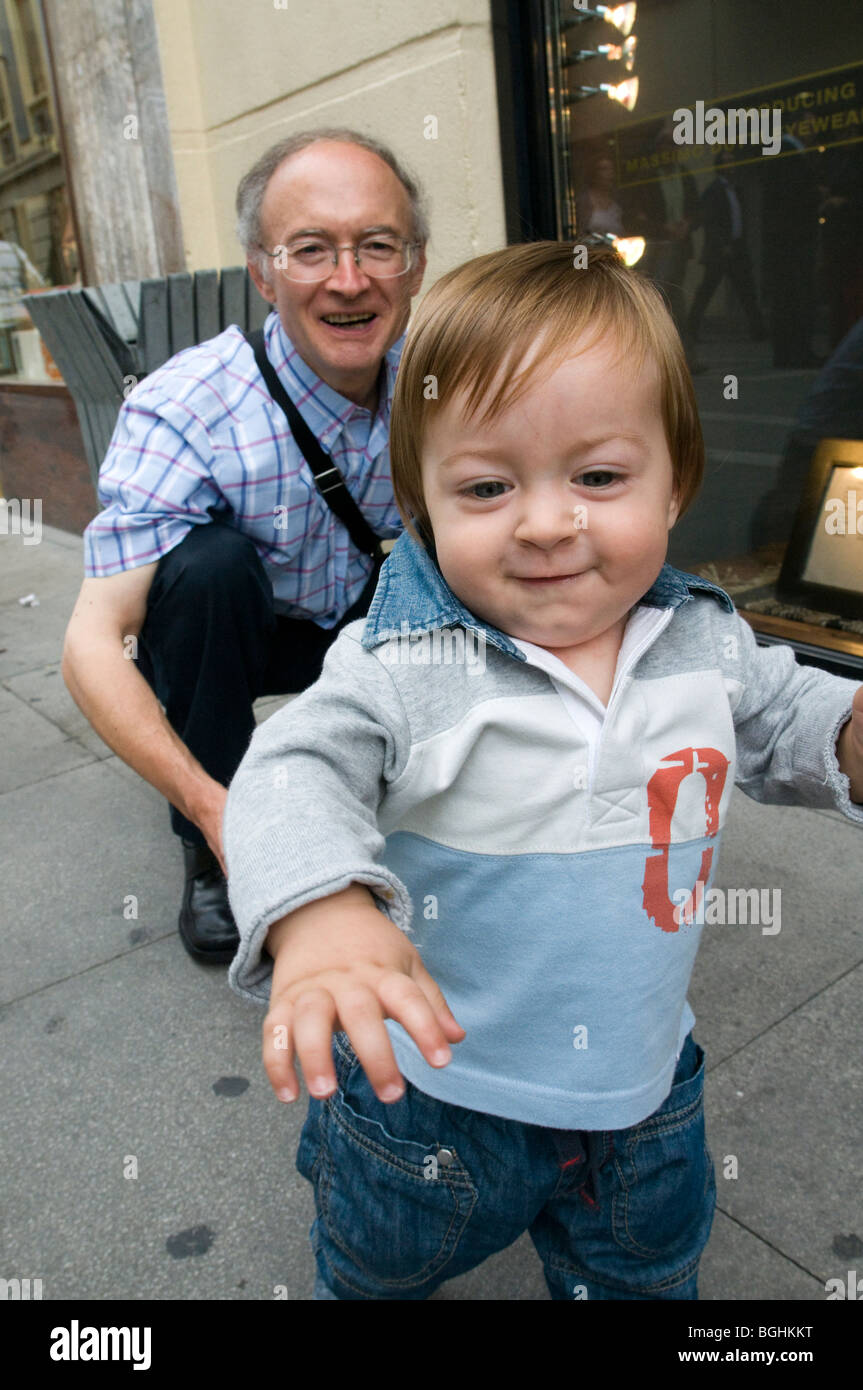 Bébé d'un an marche avec l'aide de son grand-père Banque D'Images