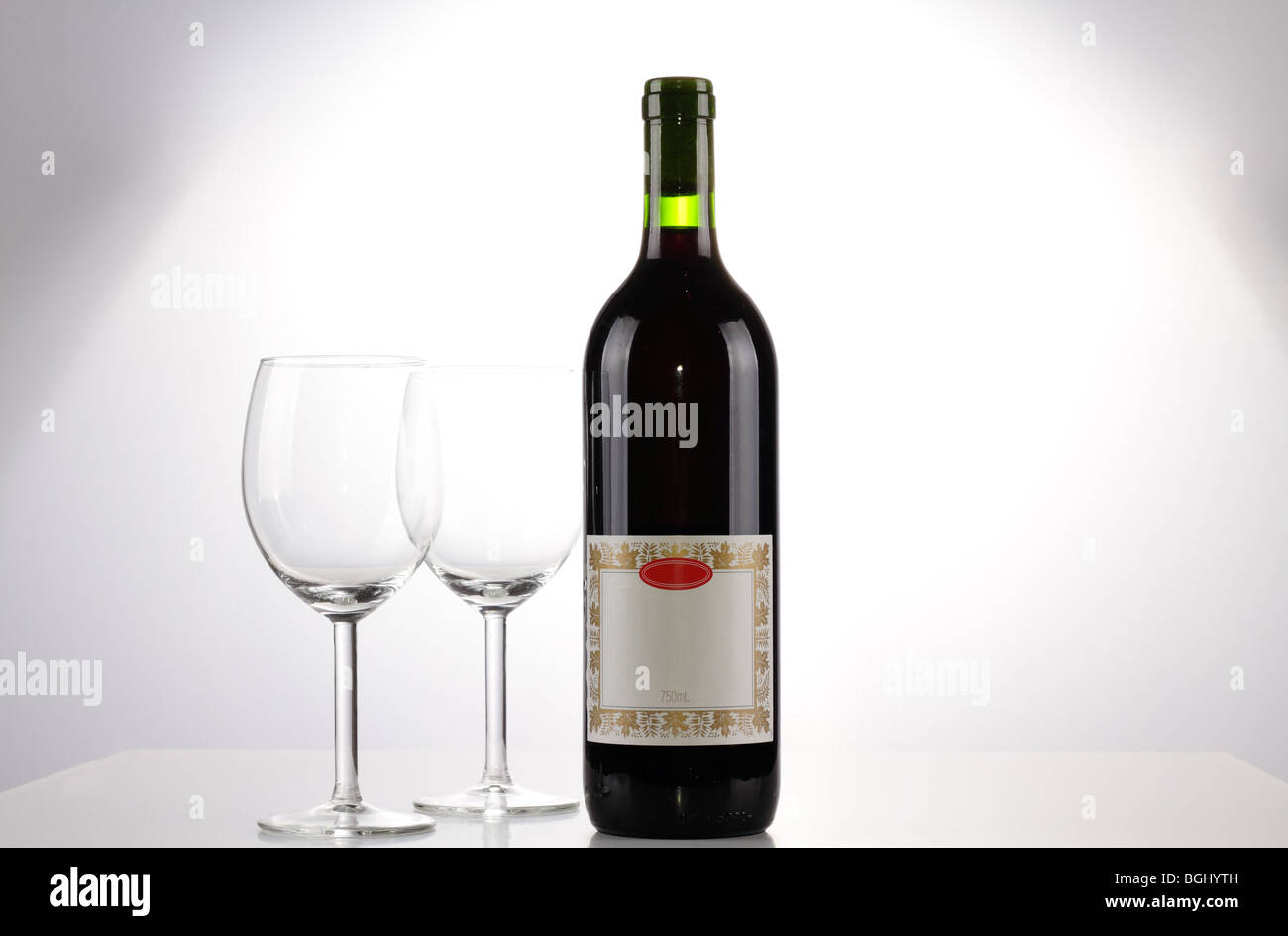 Une bouteille de vin rouge avec une étiquette vierge et deux verres de vin vide Banque D'Images