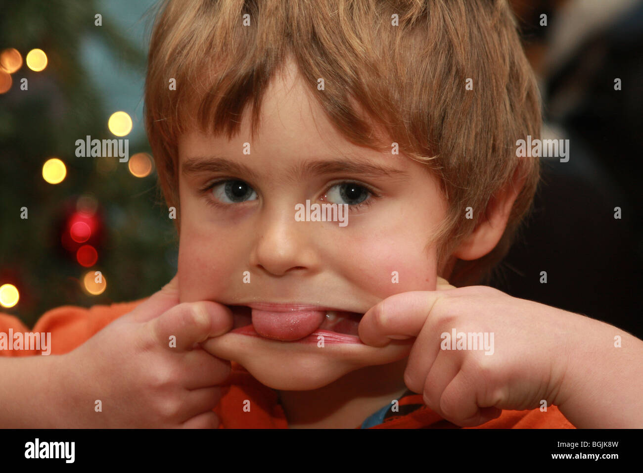 Un garçon qui sort sa langue et en tirant un visage Banque D'Images
