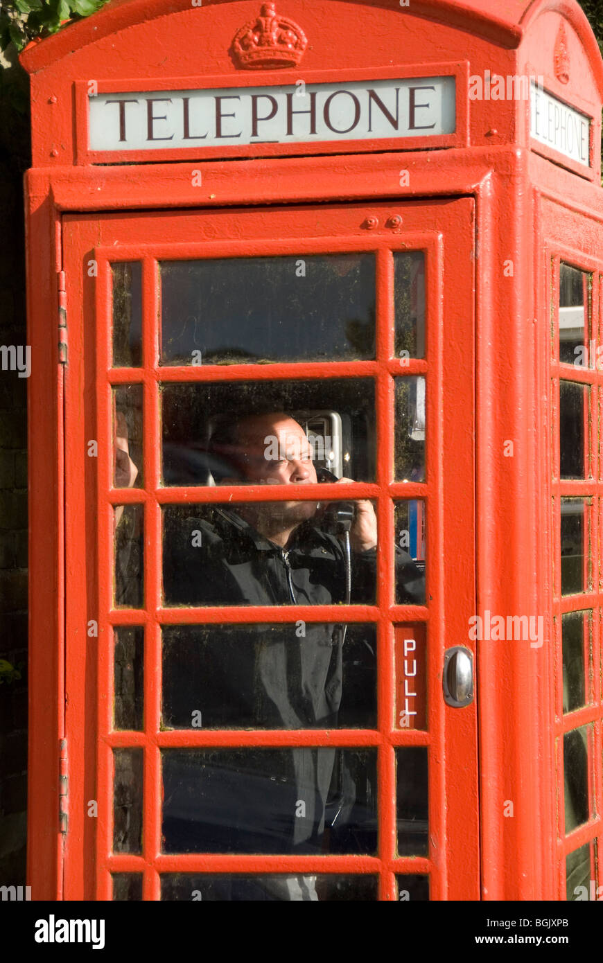 L'homme parlait au téléphone à l'intérieur d'une cabine téléphonique, England, UK Banque D'Images