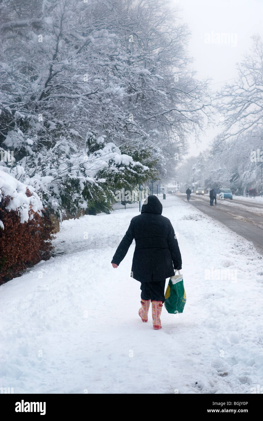 Seul piéton marchant sur le chemin couvert de neige dans les bottes. Une chute de neige importante3 domaine de hampshire janvier 2010 Banque D'Images