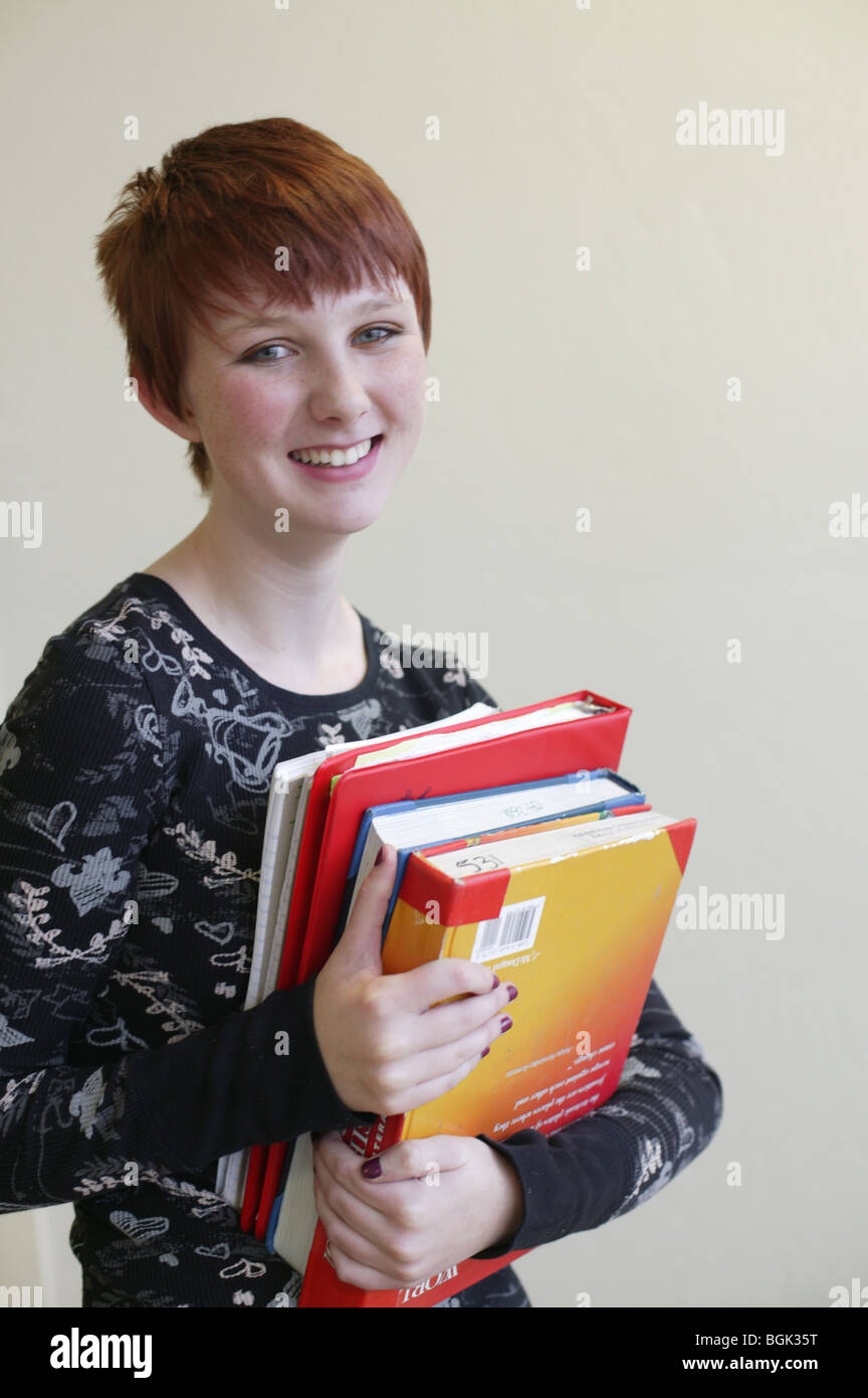 Teen girl debout tenant une pile de livres à l'école Banque D'Images