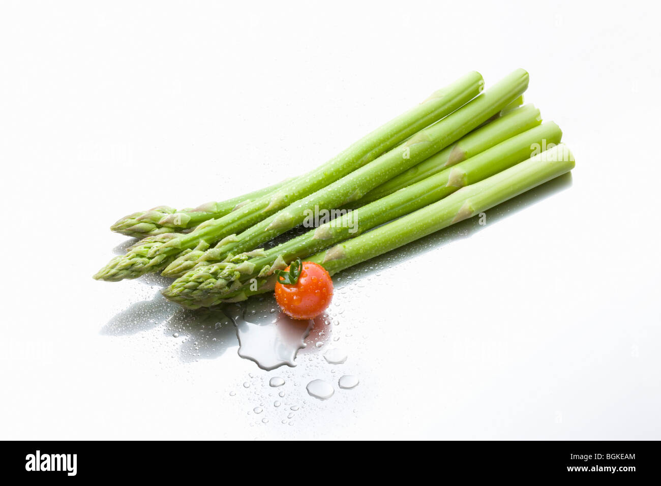 Gouttes d'eau sur les asperges et une tomate cerise Banque D'Images