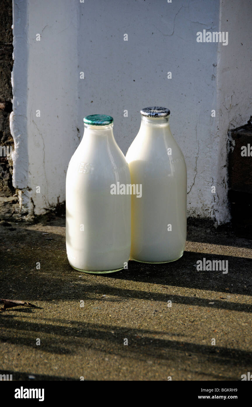 Deux bouteilles de lait complètes sur le seuil de porte, une partie supérieure verte et une partie argentée zéro déchet Banque D'Images