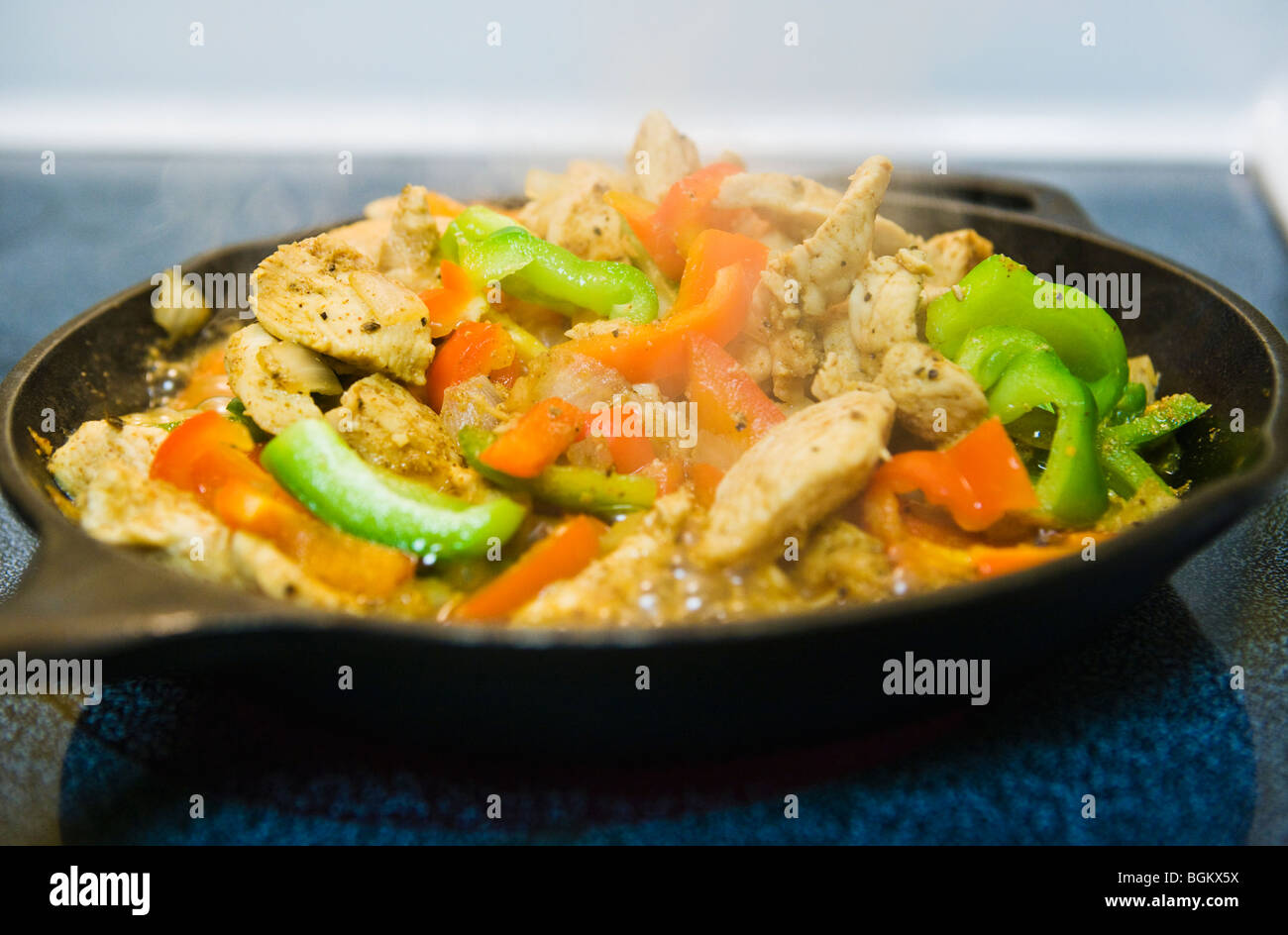 Fajitas au poulet cuisson dans une poêle de fer sur une cuisinière. Banque D'Images