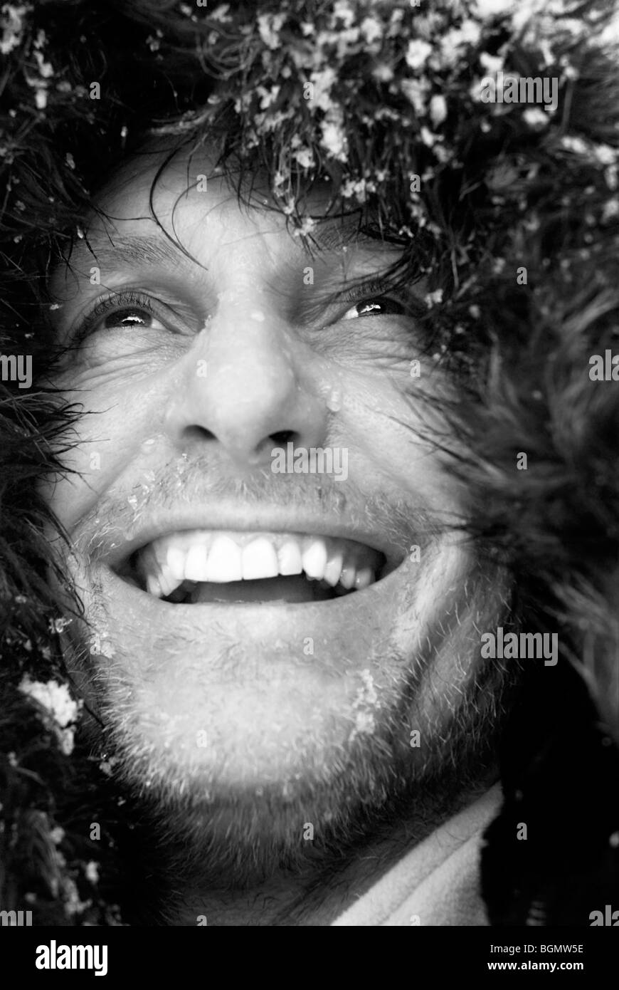 Un noir et blanc photo portrait of a happy smiling mature de la quarantaine avec des hommes portant des manteau à capuchon de fourrure ou hat Banque D'Images