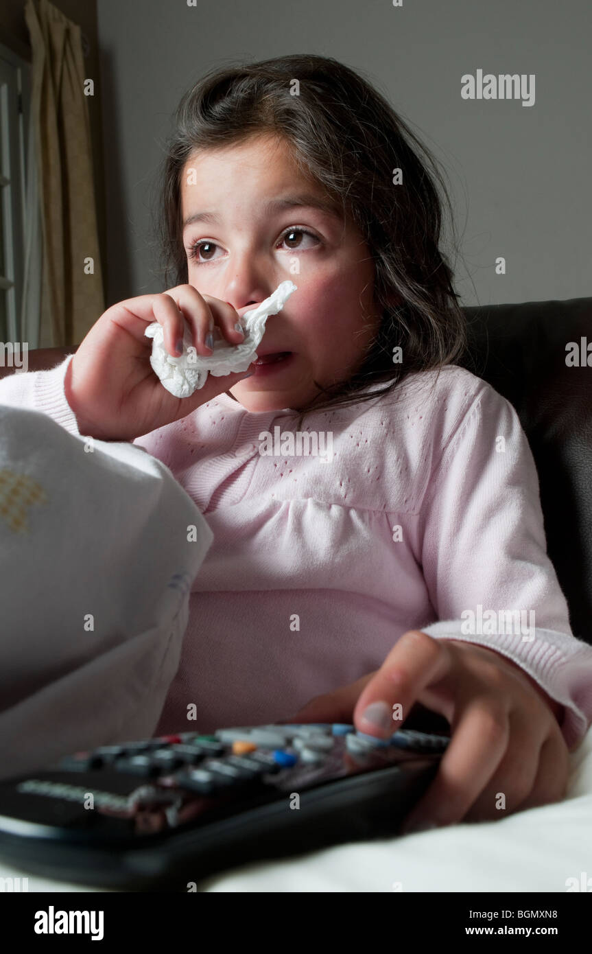 Avec un enfant assis sur le canapé froid télécommande dans la main Banque D'Images
