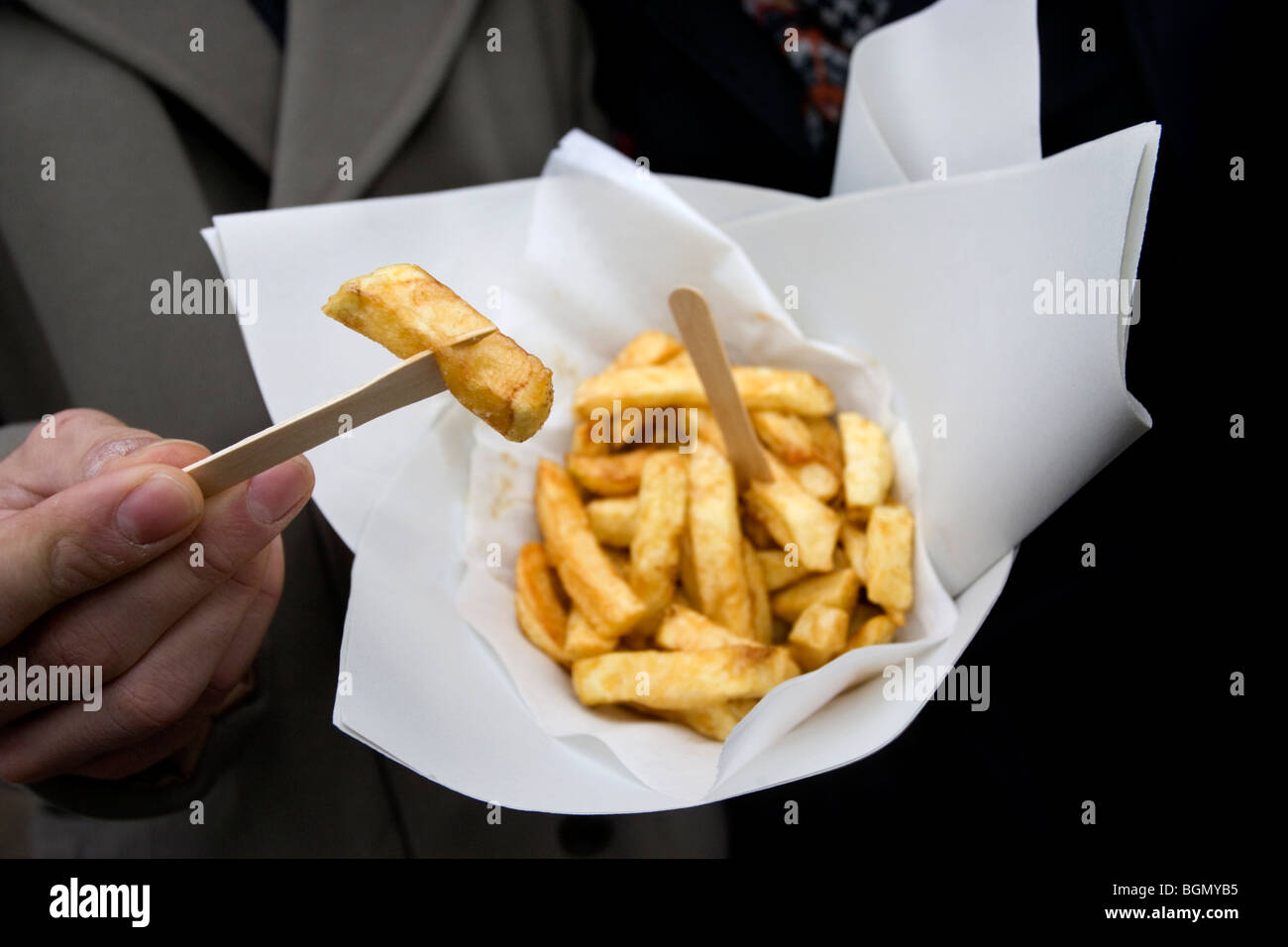 Un jeune couple profitez d'une petite portion de frites à l'extérieur traditionnel des banquiers et de poissons restaurant et Puce à emporter, Brighton, Royaume-Uni. Banque D'Images