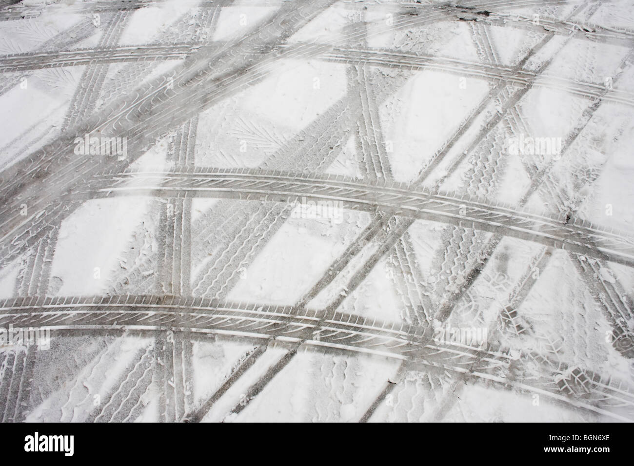 Abstract pneu (pneu) pistes de voie sont laissés comme motifs abstraits dans la neige après le mauvais temps dans un parking de supermarché. Banque D'Images
