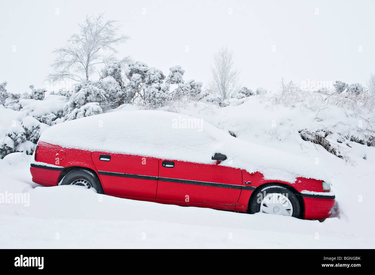 Une voiture rouge coincée dans la neige et abandonnée sur une route de campagne près de Knighton, Powys, pays de Galles, Royaume-Uni Banque D'Images