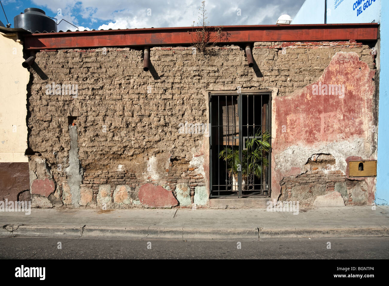 Vieille maison adobe embourgeoisés avec des restes de plâtre de couleur pâle magnifique et élégant en fer forgé ancienne porte ouverture d'Oaxaca Banque D'Images