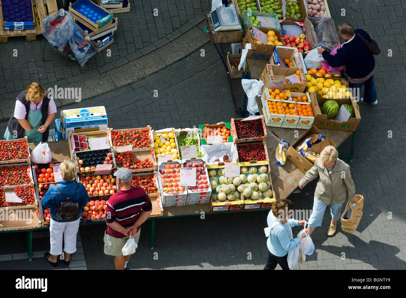 Les clients cherchant à la fruit à l'affiche au marché frais Banque D'Images