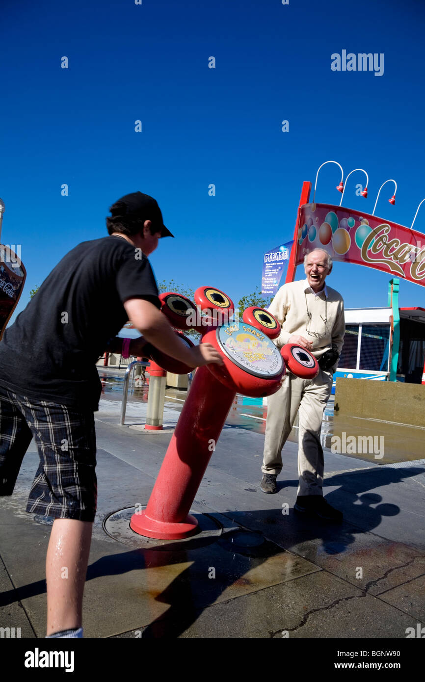 Homme plus âgé de rire de jeune garçon se mettre à l'eau à la machine à coke soak Universal Studios Hollywood Los Angeles, États-Unis. Banque D'Images