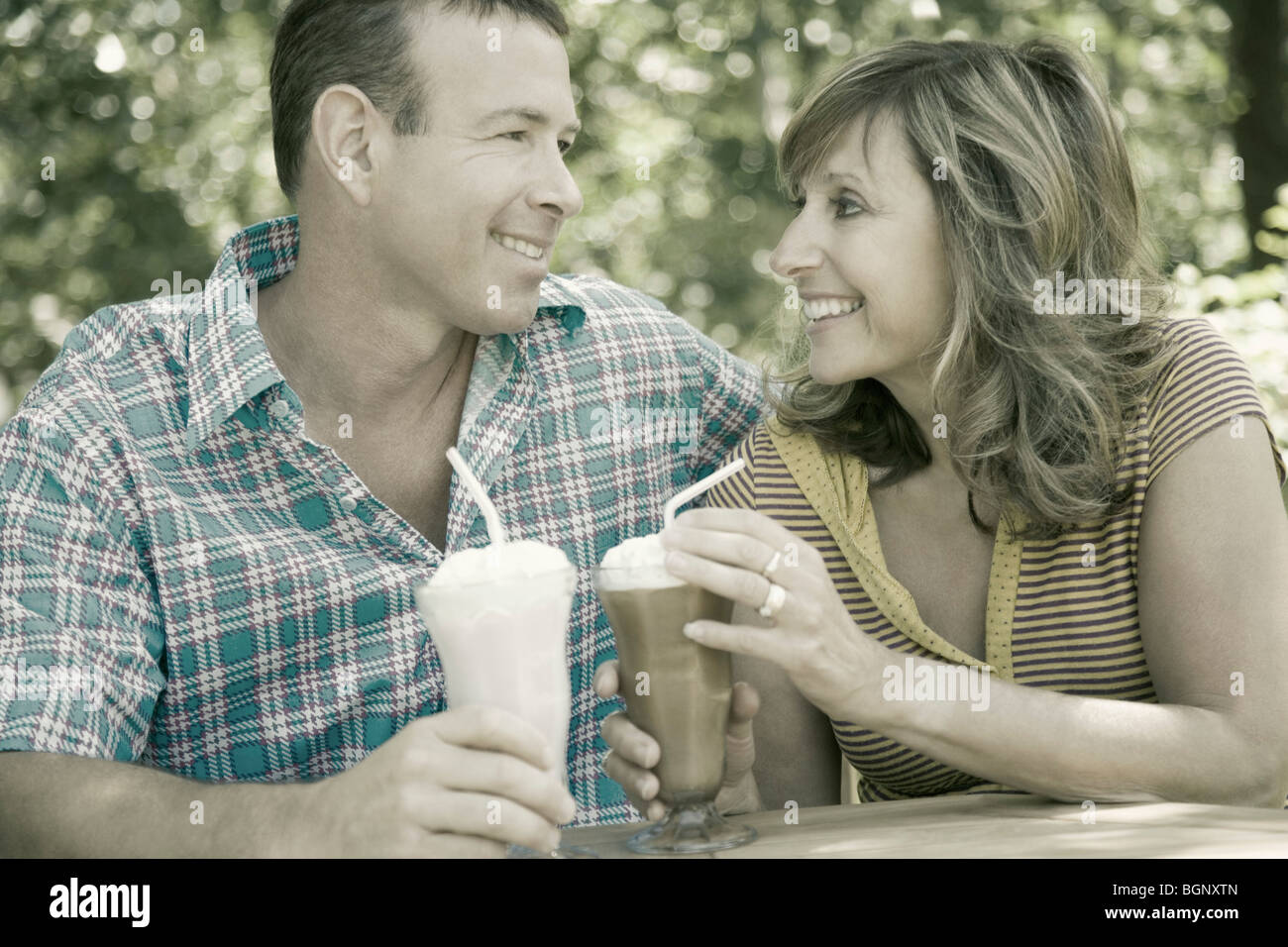 Close-up of a young couple holding milk-shakes and smiling Banque D'Images