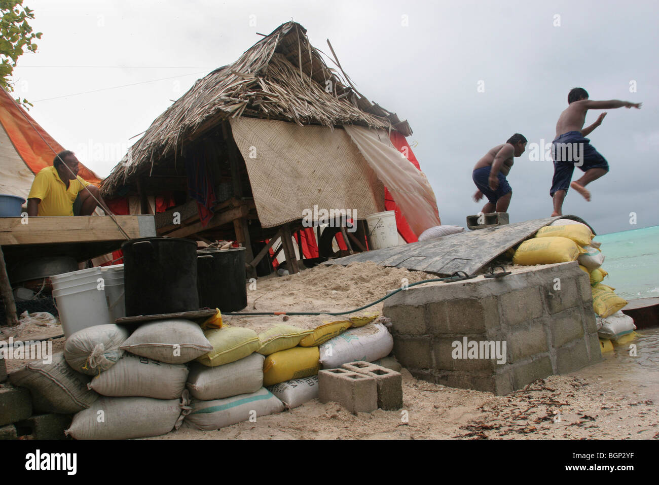 Une famille vivant près de la mer, sur l'île du Pacifique de Kiribati, de renforcer leur propriété avec un mur fait de la mer de sable. Banque D'Images