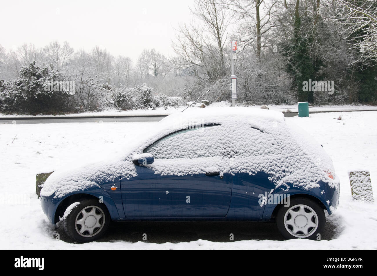 Petite voiture bleue recouverte de neige par le côté d'une route dans la région de Kent, Angleterre Banque D'Images