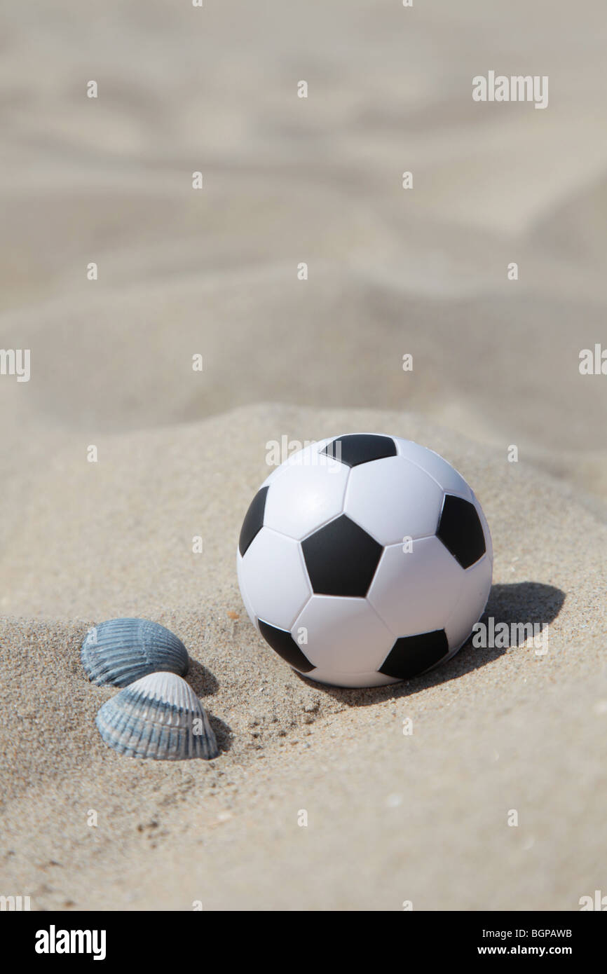 Un ballon de football situé dans le sable sur la plage Banque D'Images
