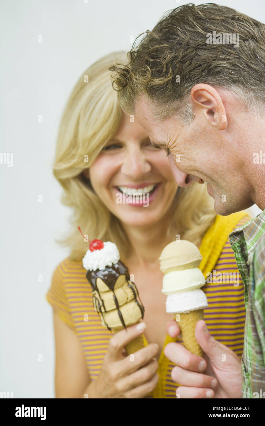 Close-up of a young couple holding ice cream cones and smiling Banque D'Images