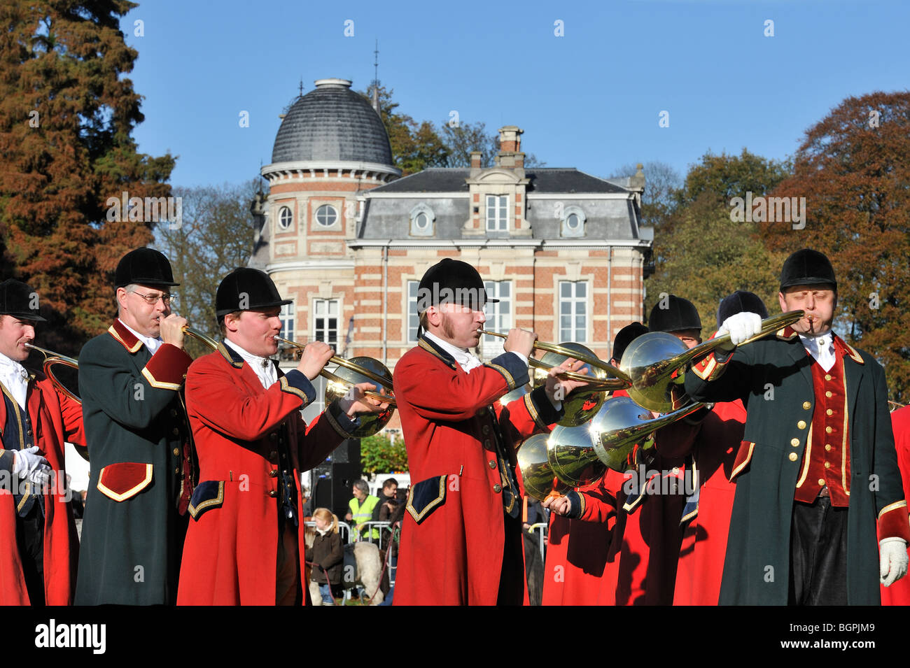 Les chasseurs portant manteaux rouges avec cors de chasse / bugles durant la commémoration de Saint Hubert / Saint Hubertus en Belgique en automne Banque D'Images