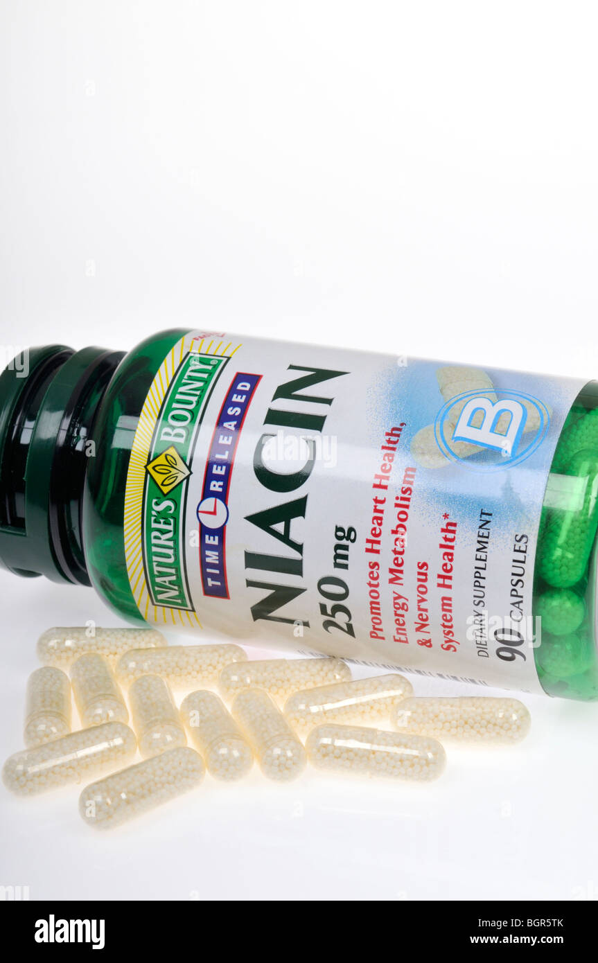 Une bouteille de niacine suppléments alimentaires portant sur le côté avec quelques capsules éparpillés sur fond blanc, découpe. Banque D'Images