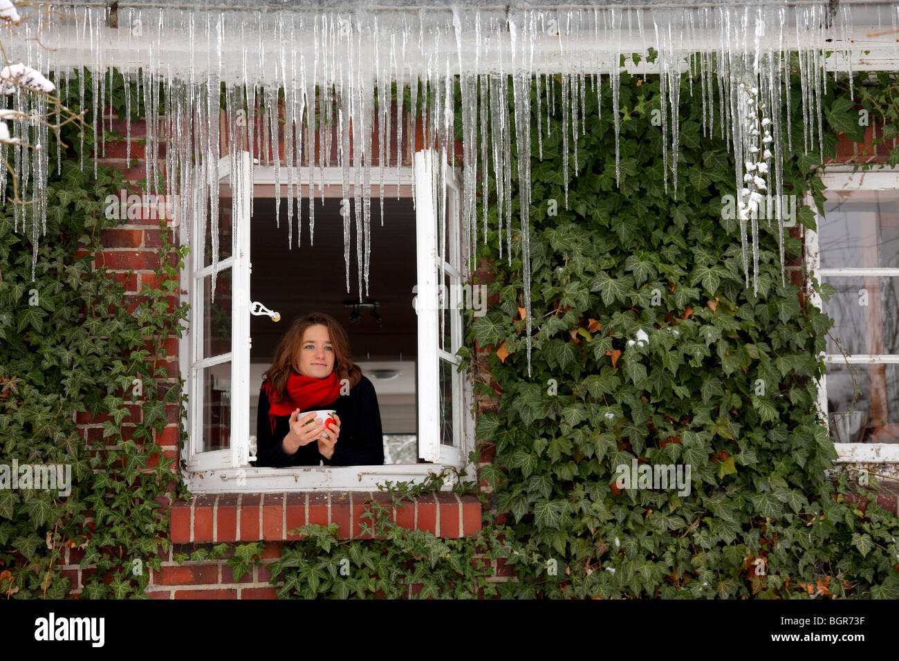 Jeune femme regardant par la fenêtre dans l'hiver Banque D'Images