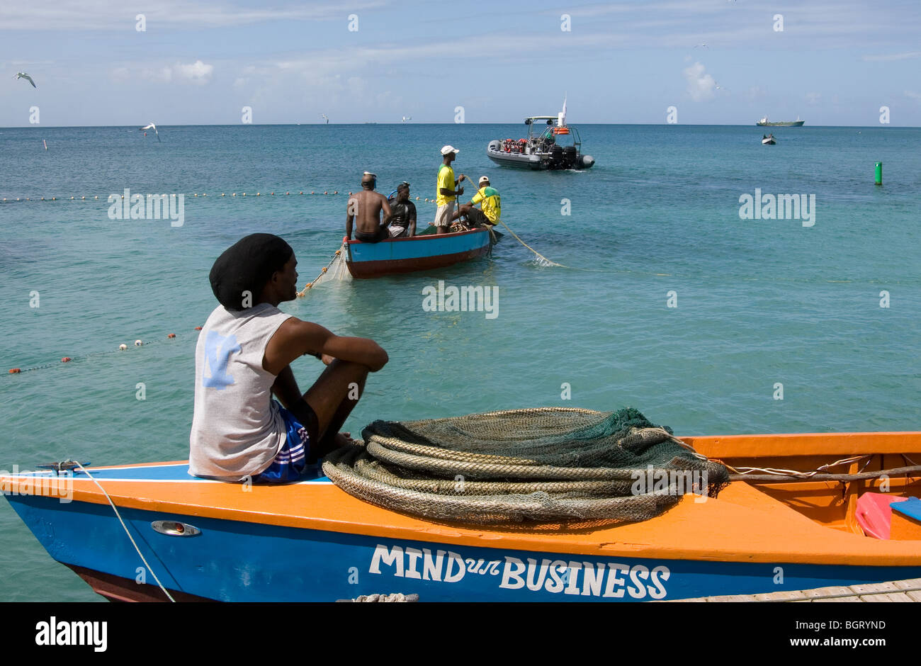 L'esprit Ur Business - Single Figure assis sur un bateau en regardant les pêcheurs dans les Antilles. Banque D'Images