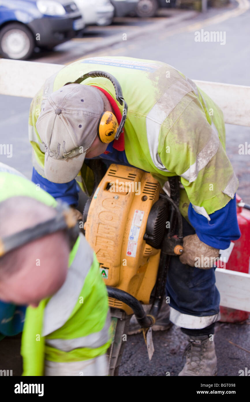 Workman creuser dans les conduites de gaz avec un marteau pneumatique. Banque D'Images