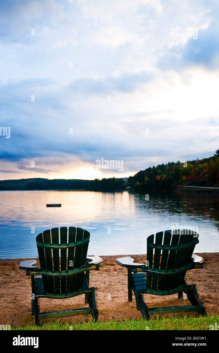 Deux chaises en bois sur la plage du lac de détente au coucher du soleil Banque D'Images