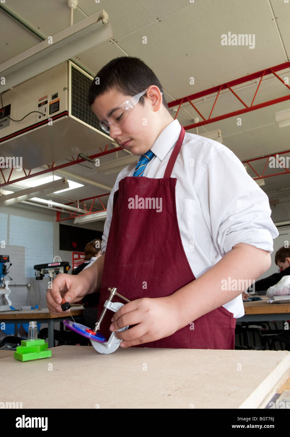 Teenage boy wearing apron et lunettes de protection design & Technology Workshop Balcarras School Cheltenham UK Banque D'Images