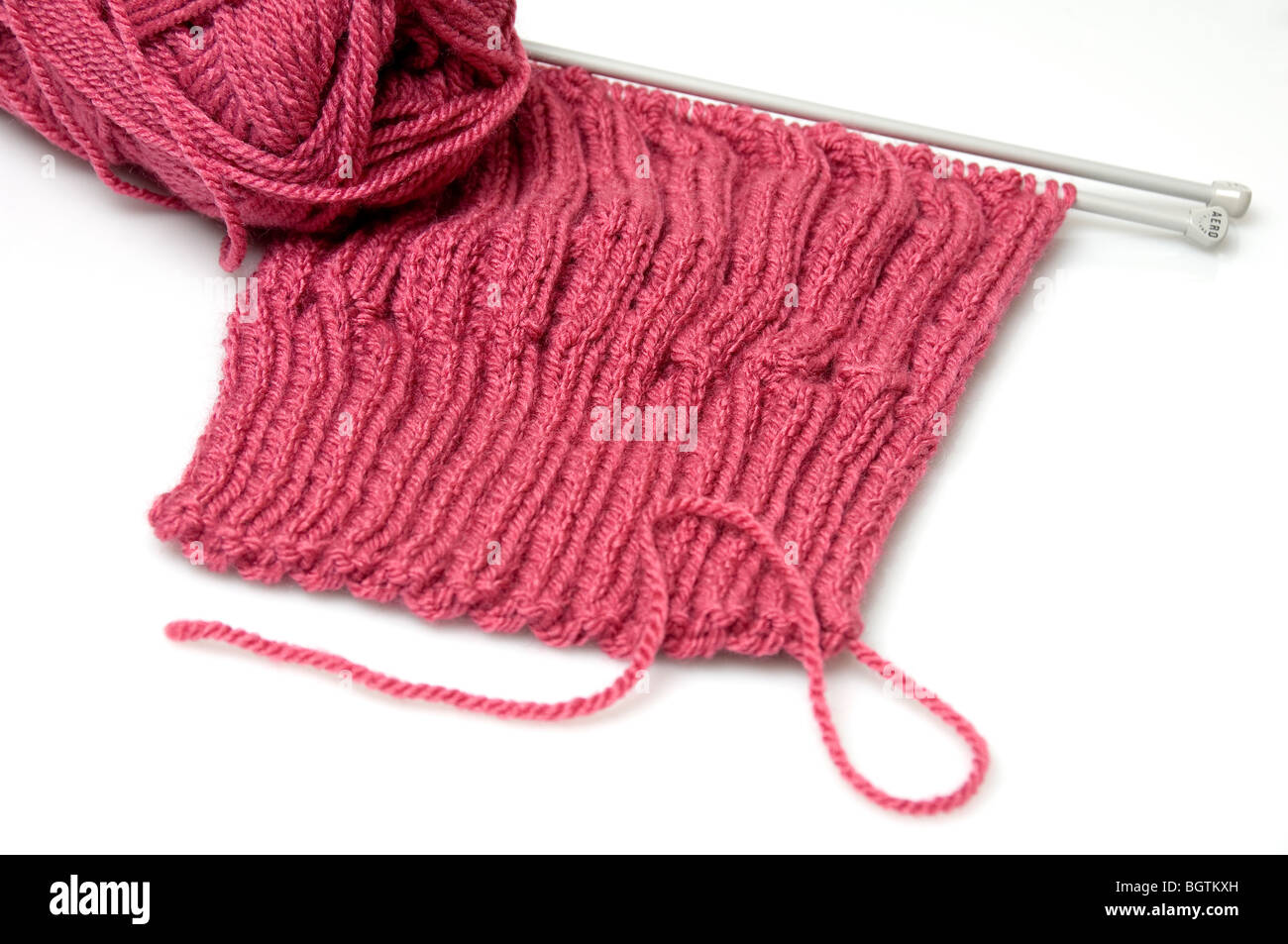 Gros plan de tricotage avec des aiguilles et une boule de laine rose sur fond blanc Banque D'Images