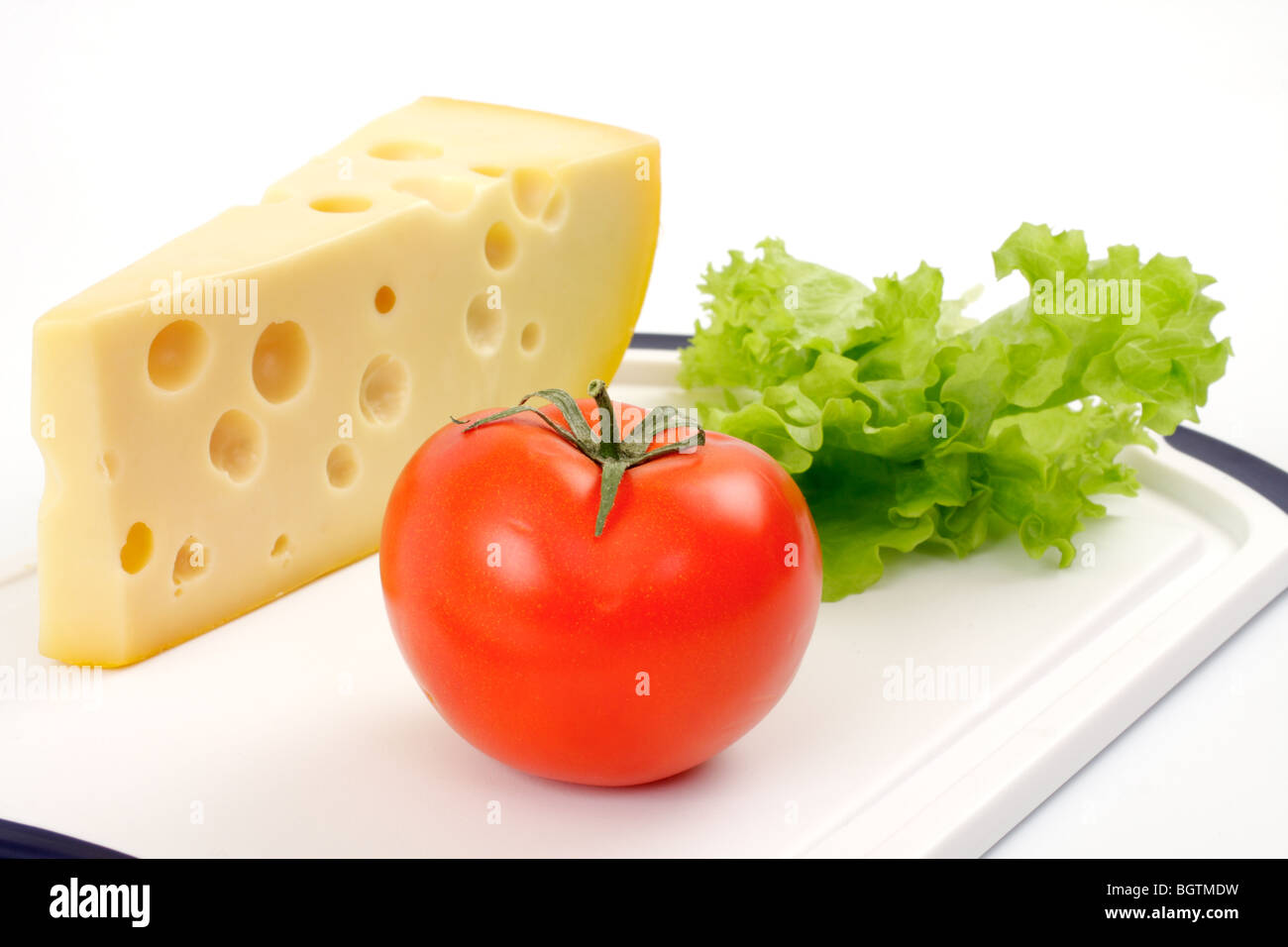 Fromage, tomate et salade feuille sur un tableau blanc isolé studio. Banque D'Images