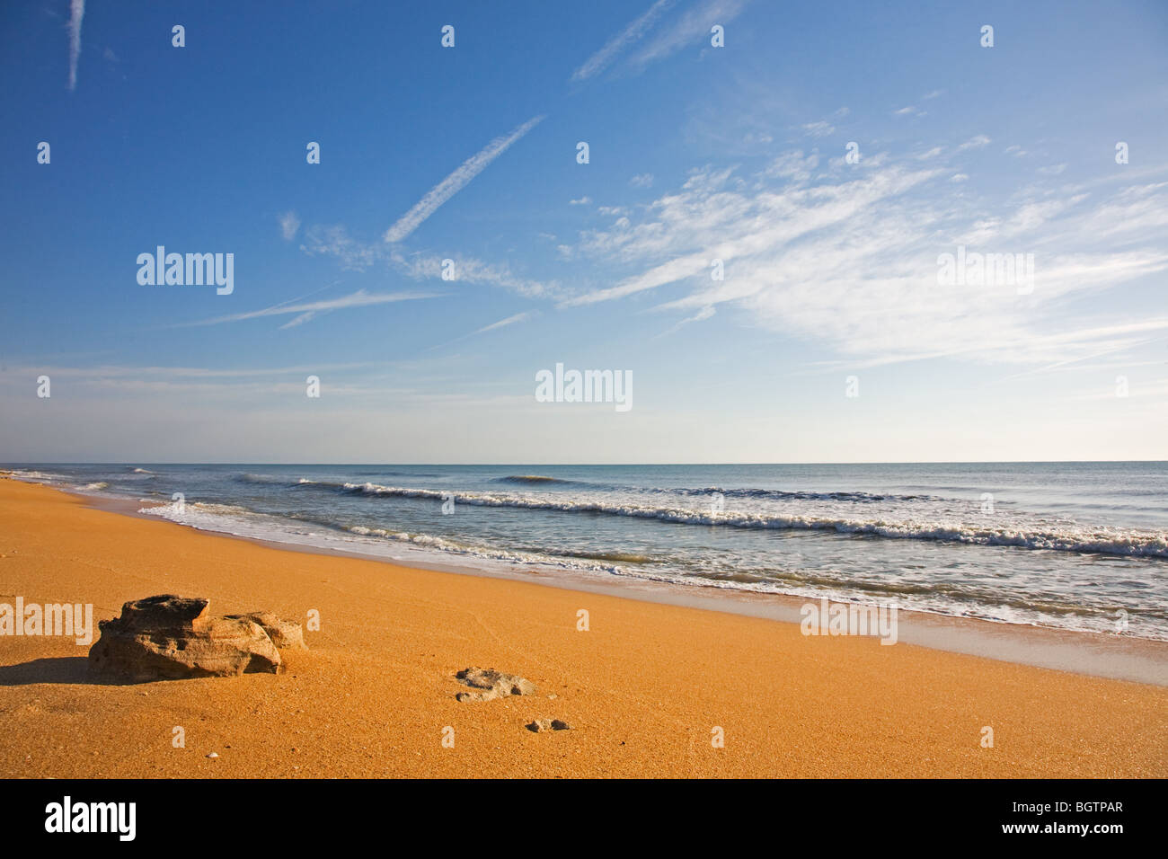 Tôt le matin, la lumière sur le sable de couleur riche et la plage de surf Banque D'Images