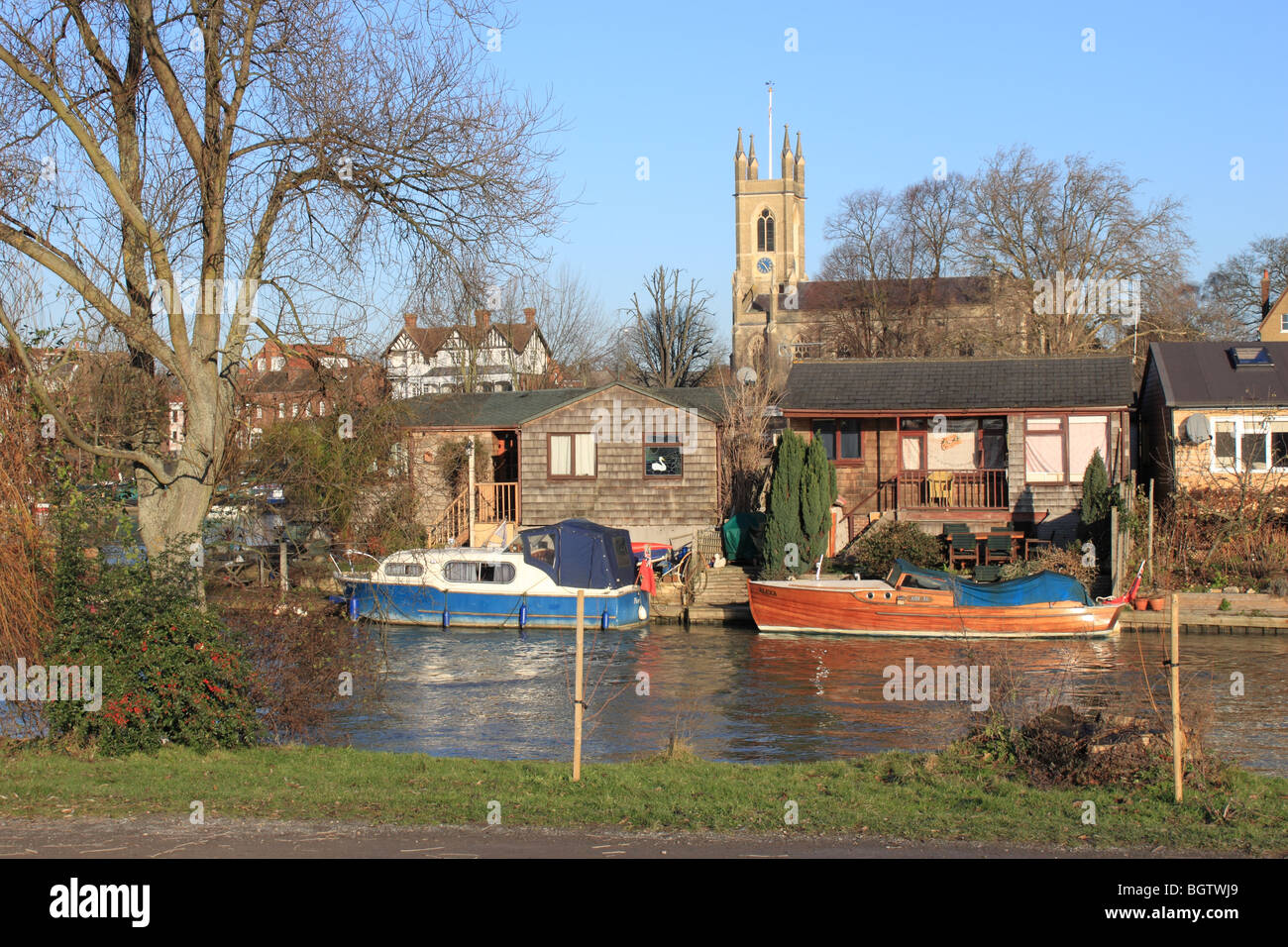 Des bateaux et des maisons de vacances sur l'île de Garrick's Aci, Tamise, East Molesey, Angleterre, Royaume-Uni, Europe. Hampton church de l'autre côté de la rivière en arrière-plan. Banque D'Images