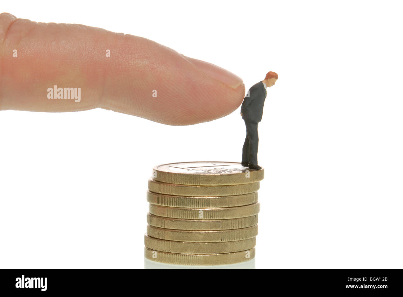 La main de l'homme pousser un homme miniature figure à partir d'une pile de pièces, image symbolique de licenciement Banque D'Images