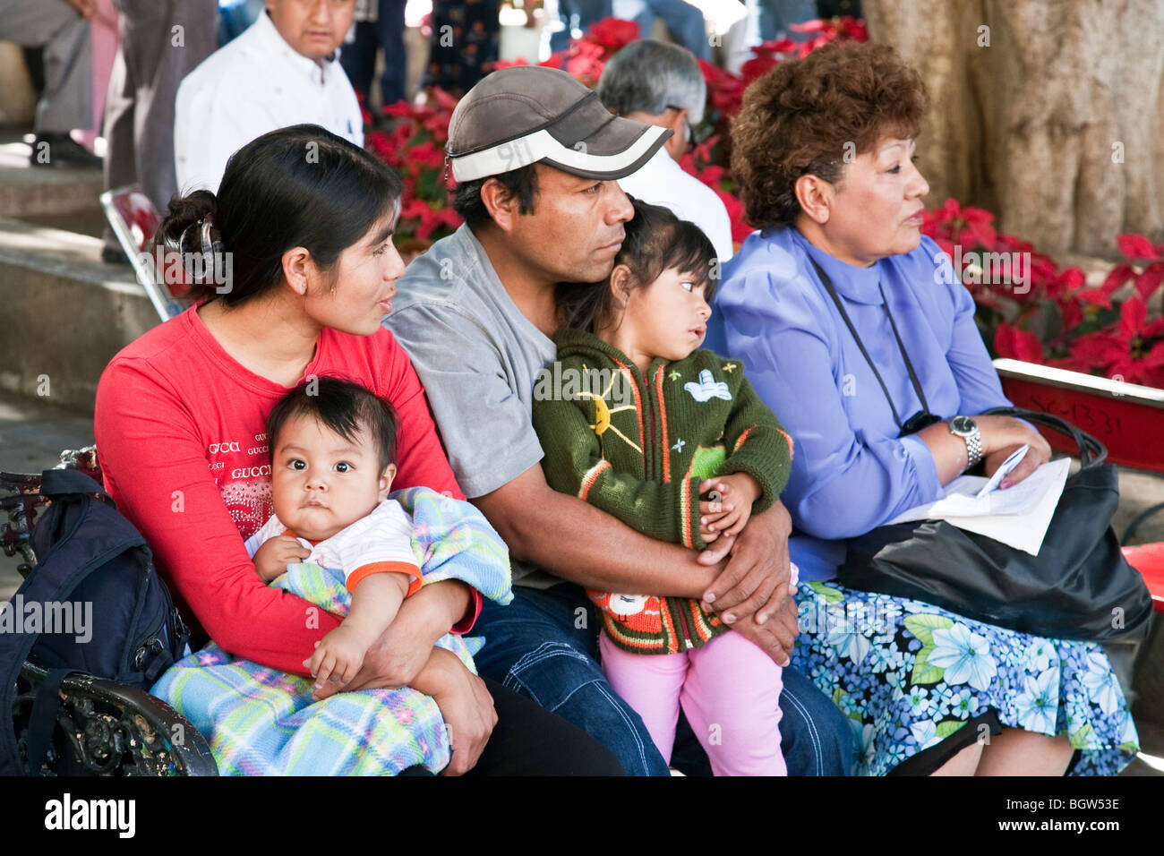 Jeune mexicaine famille avec deux enfants et grand-mère élégant assis en public lors de concert du dimanche dans la ville d'Oaxaca Zocalo Banque D'Images