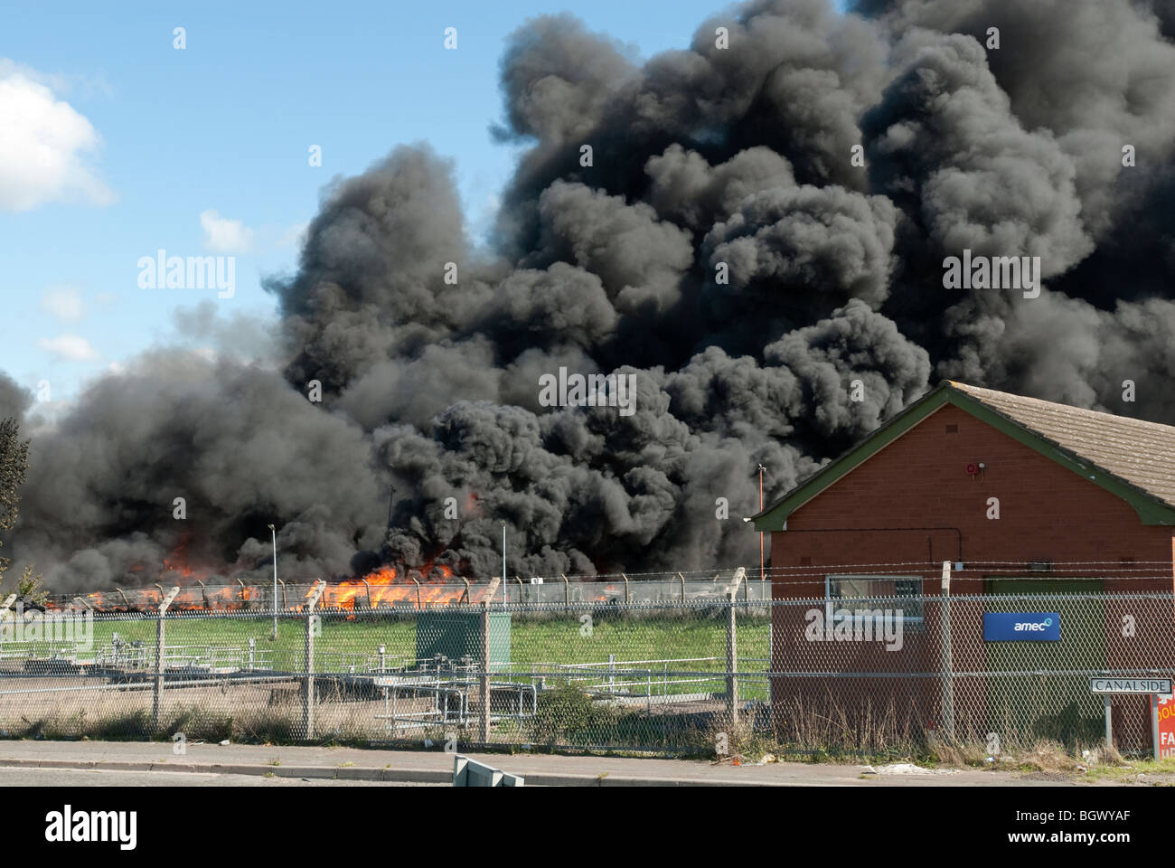 Les incendies industriels énormes avec de grands panaches de fumée noire épaisse contre le ciel bleu Banque D'Images
