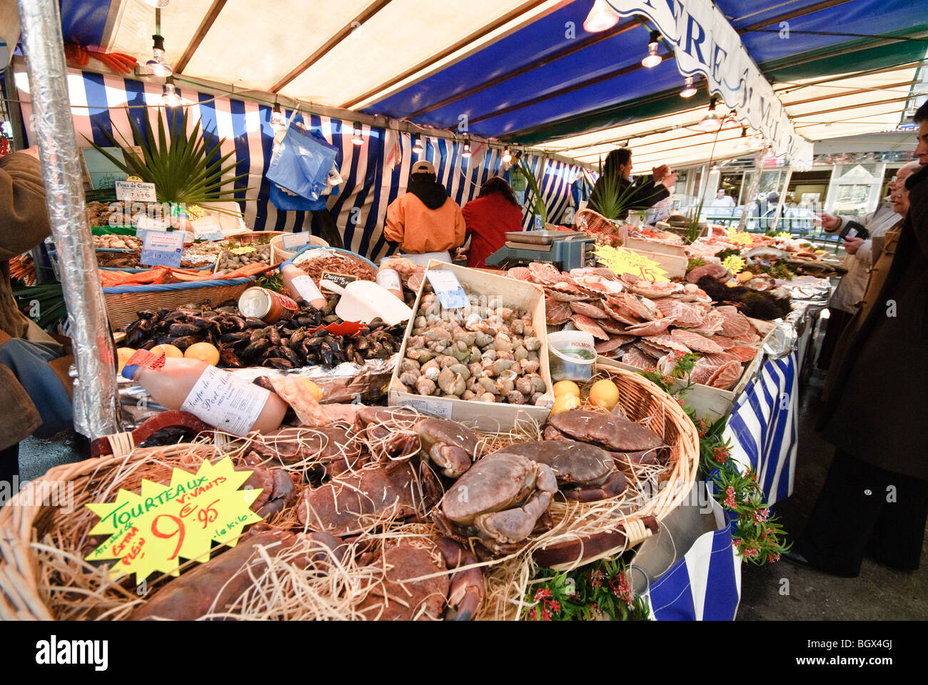 PARIS, France — Un marché parisien en plein air dynamique présente une gamme de produits frais. Les fruits et légumes colorés sont agencés avec art dans divers stands, tandis que les vendeurs et les acheteurs locaux interagissent dans cette scène traditionnelle du marché français. Banque D'Images