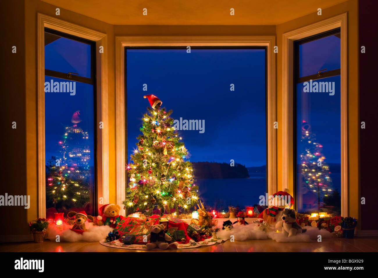 Arbre de Noël avec des lumières, décorations et cadeaux dans une fenêtre au crépuscule, les artistes Point, Hyde Creek, Port McNeill, le nord de l'Av Banque D'Images