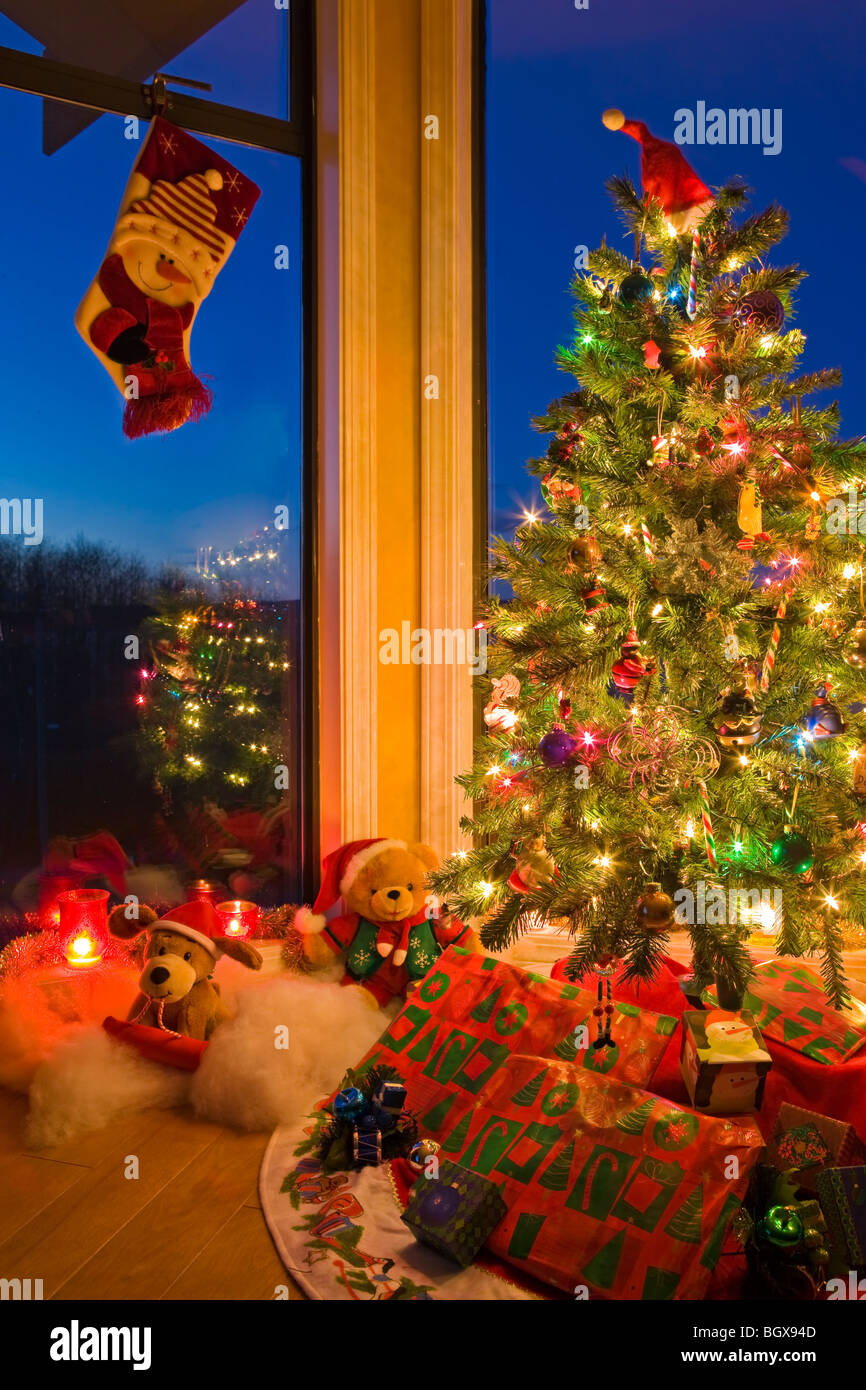 Arbre de Noël avec des lumières, des décorations, des cadeaux et un Noël de raccrocher dans une fenêtre au crépuscule, les artistes Point, Hyde Banque D'Images