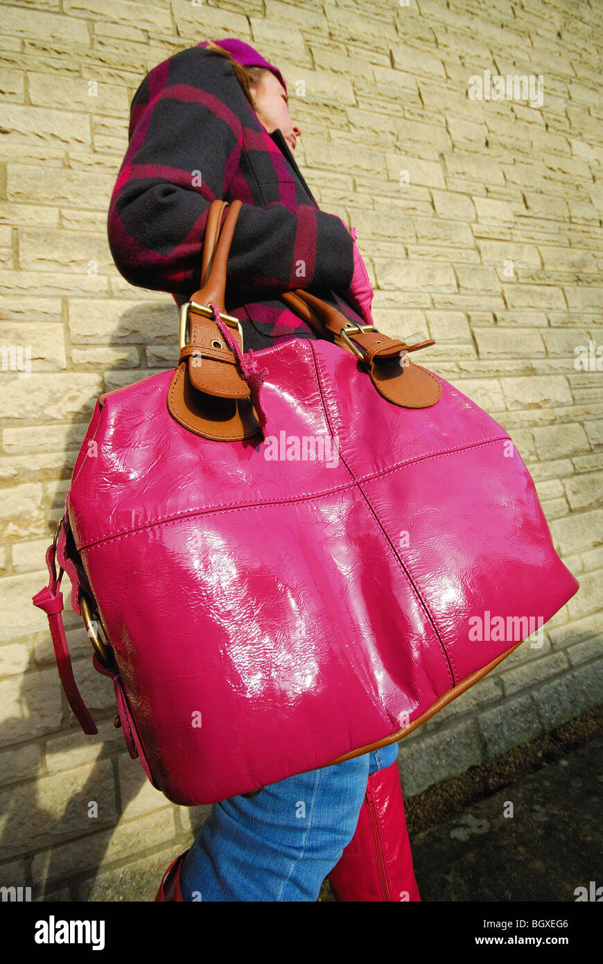 Une femme portant un brillant, rose, immense sac à main. Banque D'Images