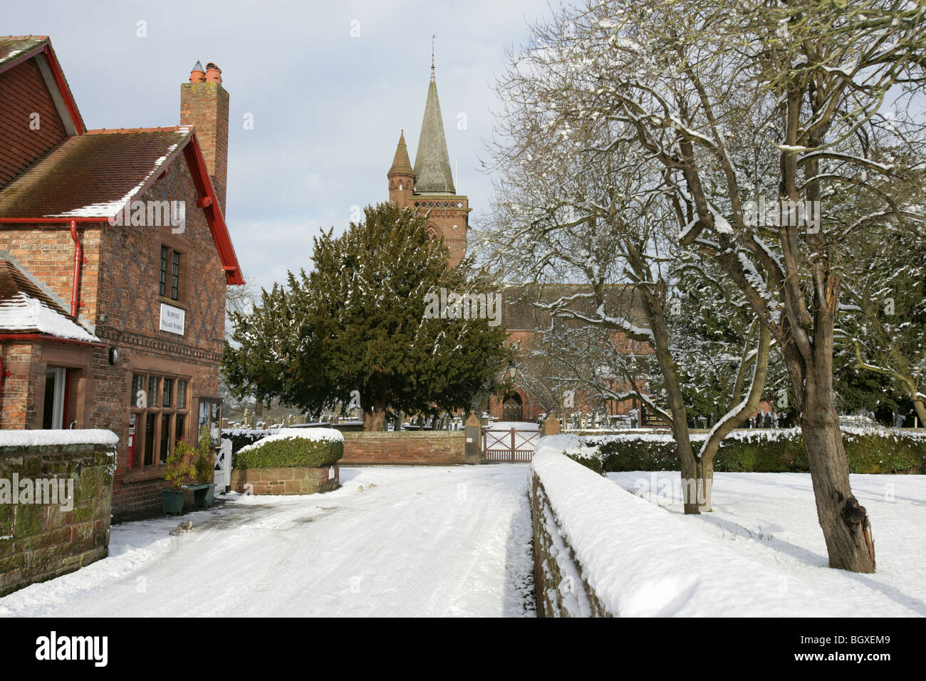 Village de Aldford, Angleterre. Compte tenu de l'hiver en milieu rural village store avec St Jean Baptiste l'église de l'arrière-plan. Banque D'Images