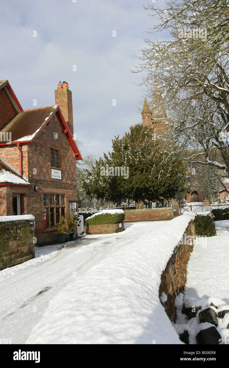 Village de Aldford, Angleterre. Compte tenu de l'hiver en milieu rural village store avec St Jean Baptiste l'église de l'arrière-plan. Banque D'Images