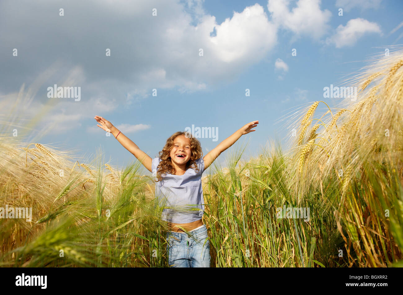Fille jouant dans un champ de blé Banque D'Images