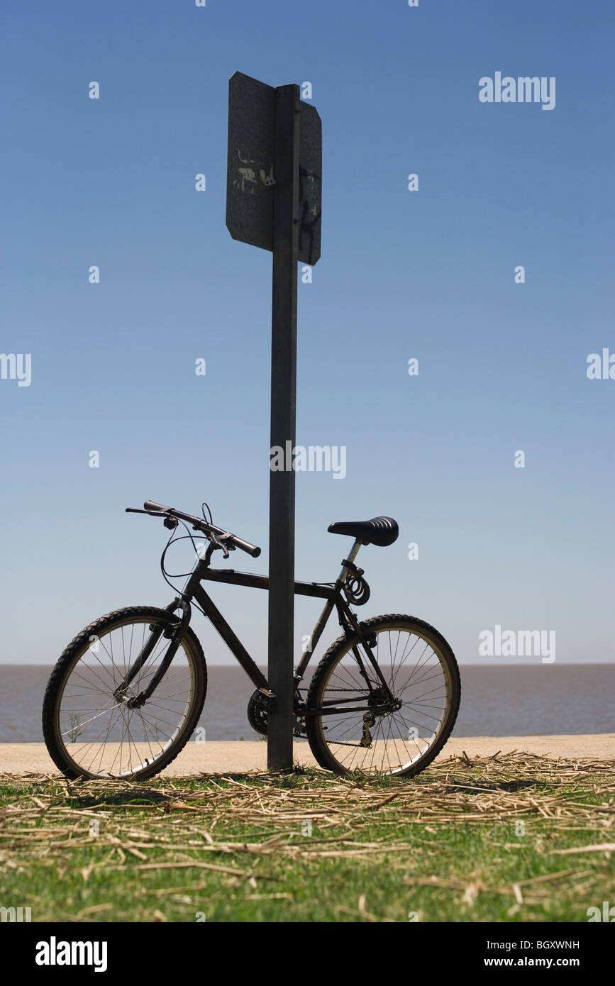 Bicycle leaning against street sign, plage en arrière-plan Banque D'Images
