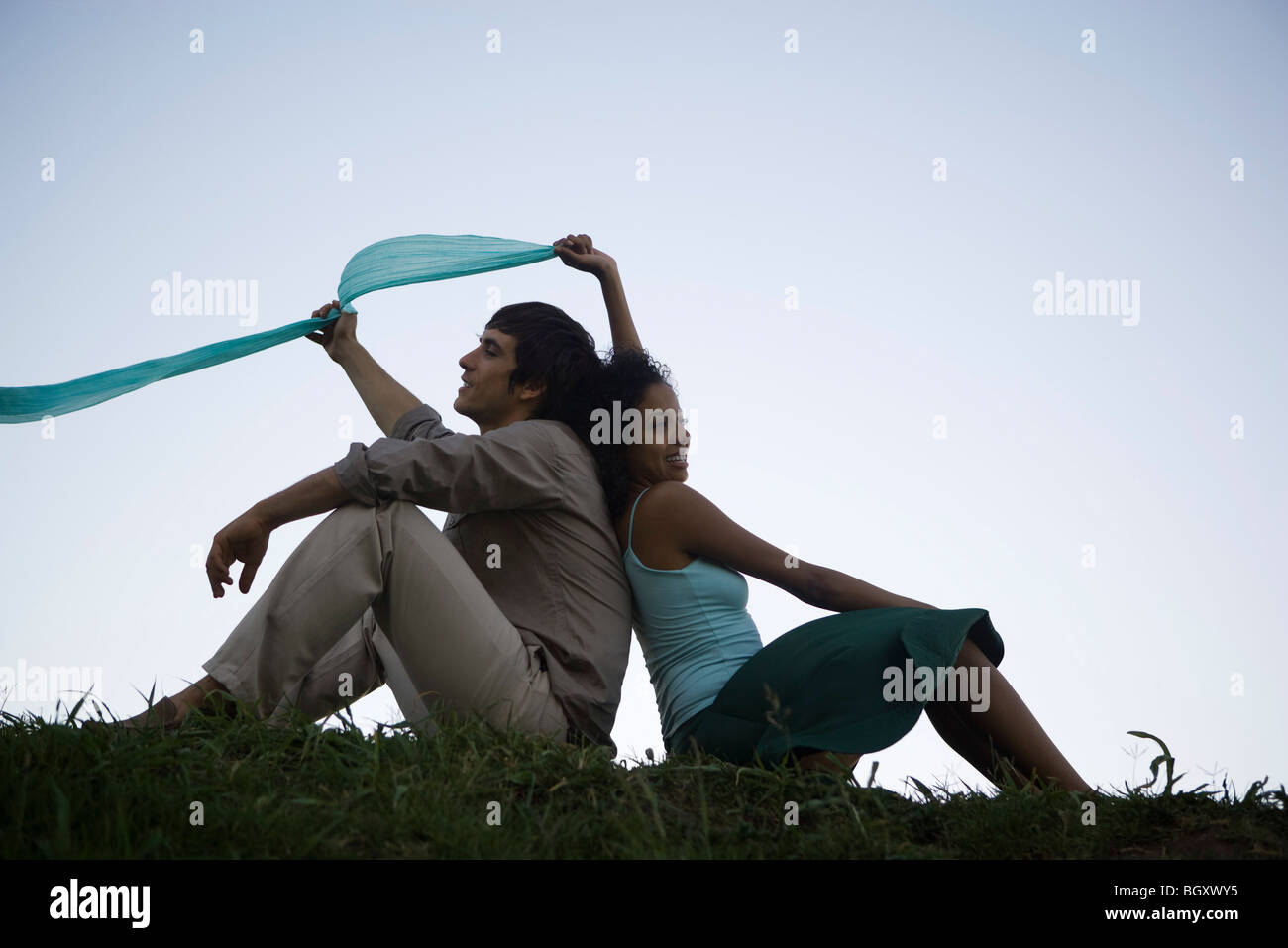 Young couple sitting in grass dos à dos Banque D'Images