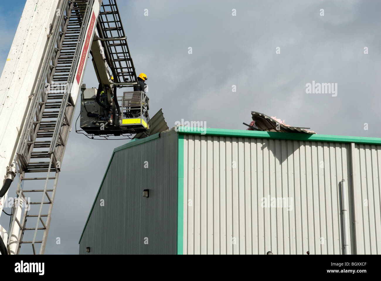 Sapeur-pompier en plate-forme hydraulique toit endommagé vent sécuritaire rend Banque D'Images
