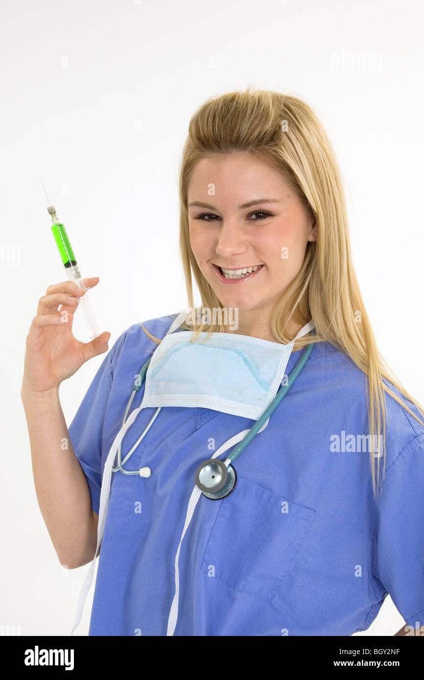 Young caucasian female nurse wearing scrubs costume et tenant une seringue hypodermique Banque D'Images